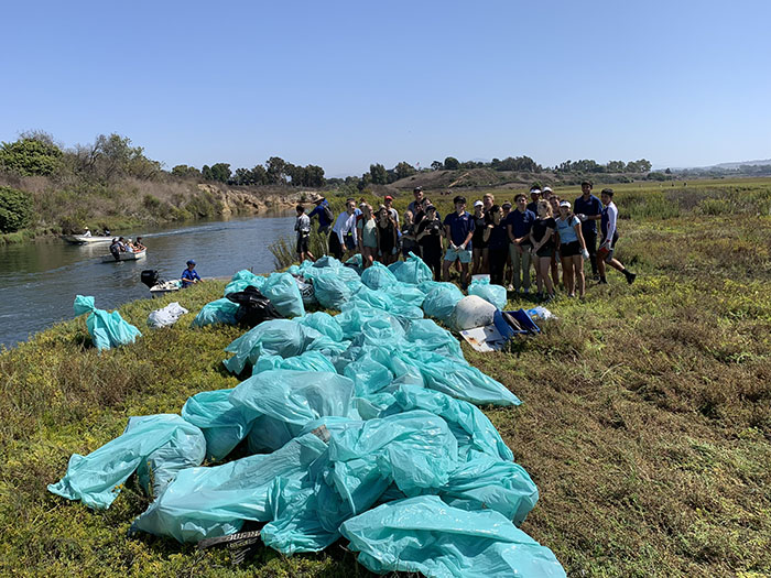 Volunteers in Newport Bay in Orange County pose for a quick photo after collecting many bags of trash at a past Coastal Cleanup Day. Photo from Newport Sea Base.